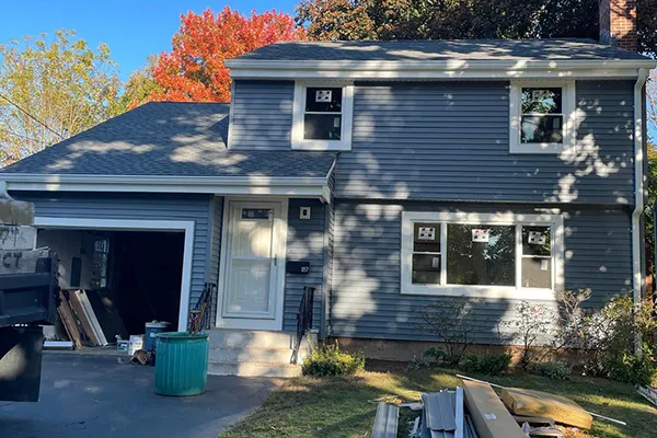 Completed blue siding house with new roof, white trim and windows