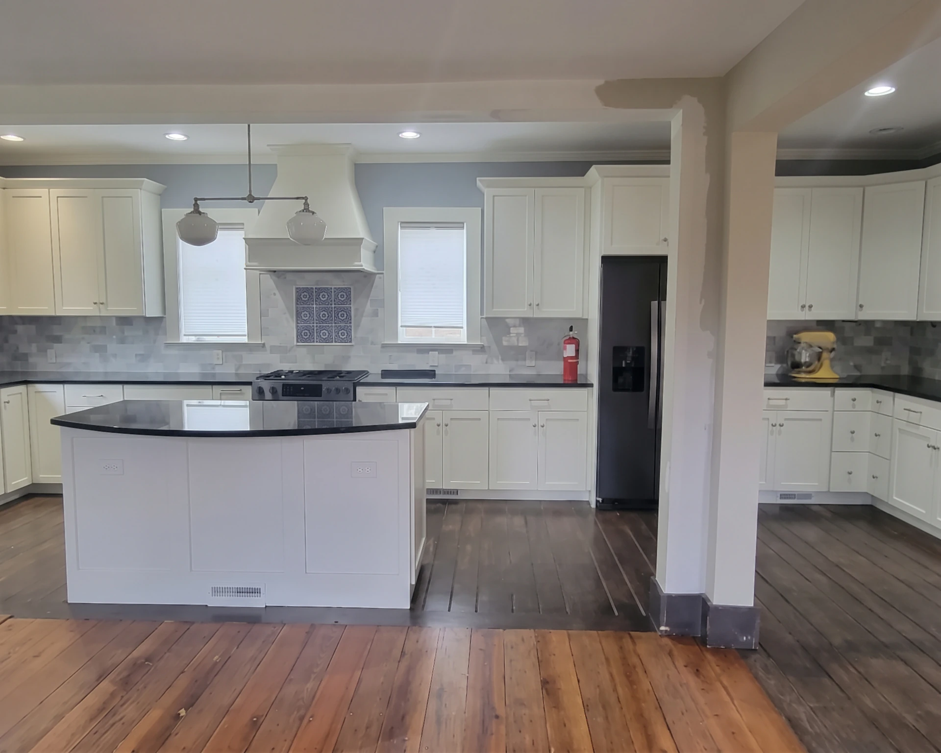 Renovated white kitchen with black granite island and gray tile backsplash