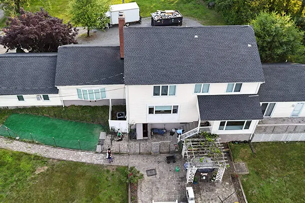 Aerial view of white Connecticut house with new dark gray shingle roof and patio